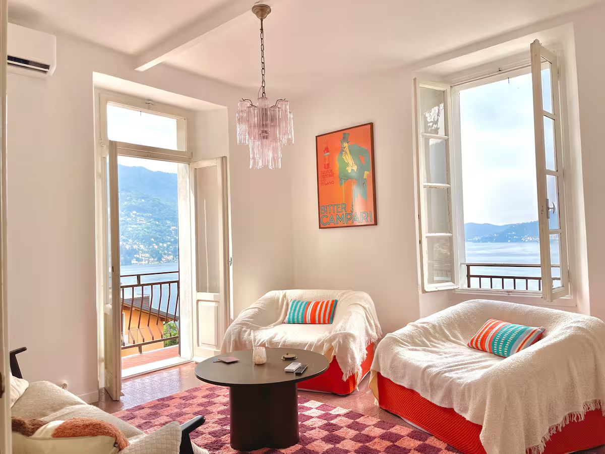 Living room with open windows framing Lake Como